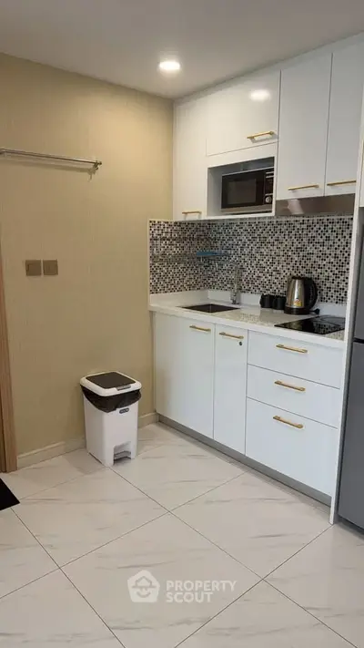 Modern kitchen with sleek white cabinets and mosaic backsplash in a compact layout.