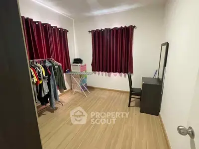 Cozy room with wooden flooring, red curtains, and a small dressing area.