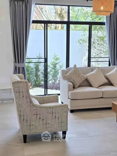 Elegant living room with modern furniture and large windows overlooking a garden.