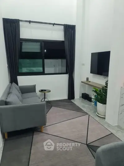 Modern living room with sleek gray sofa, stylish rug, and wall-mounted TV for contemporary comfort.