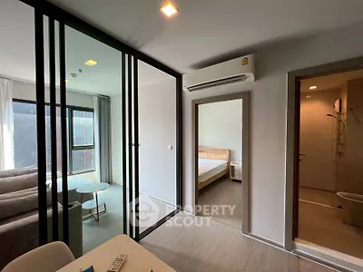 Modern apartment interior with glass partition, cozy living room, and bedroom view.