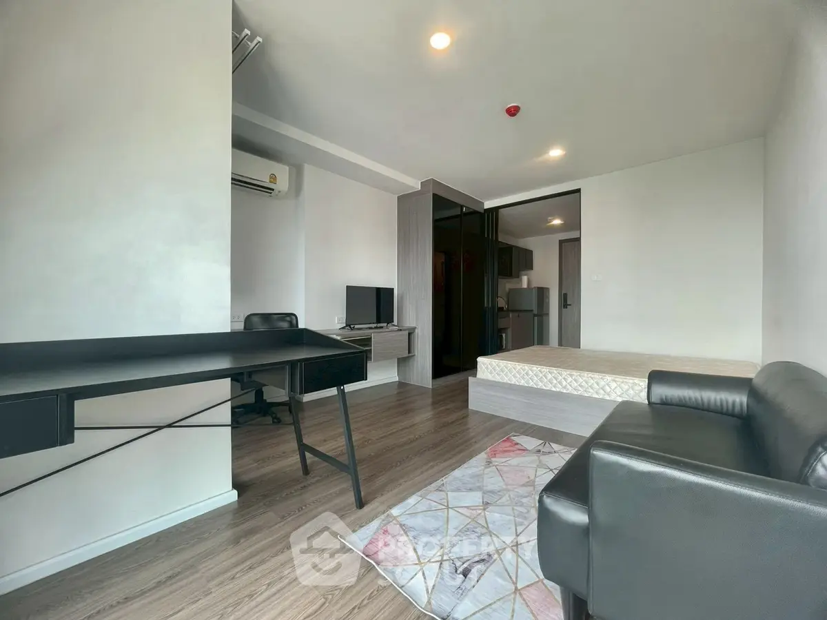 Modern studio apartment with sleek furniture and open layout, featuring a cozy workspace and comfortable living area.