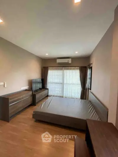 Spacious bedroom with modern furnishings and large window for natural light.