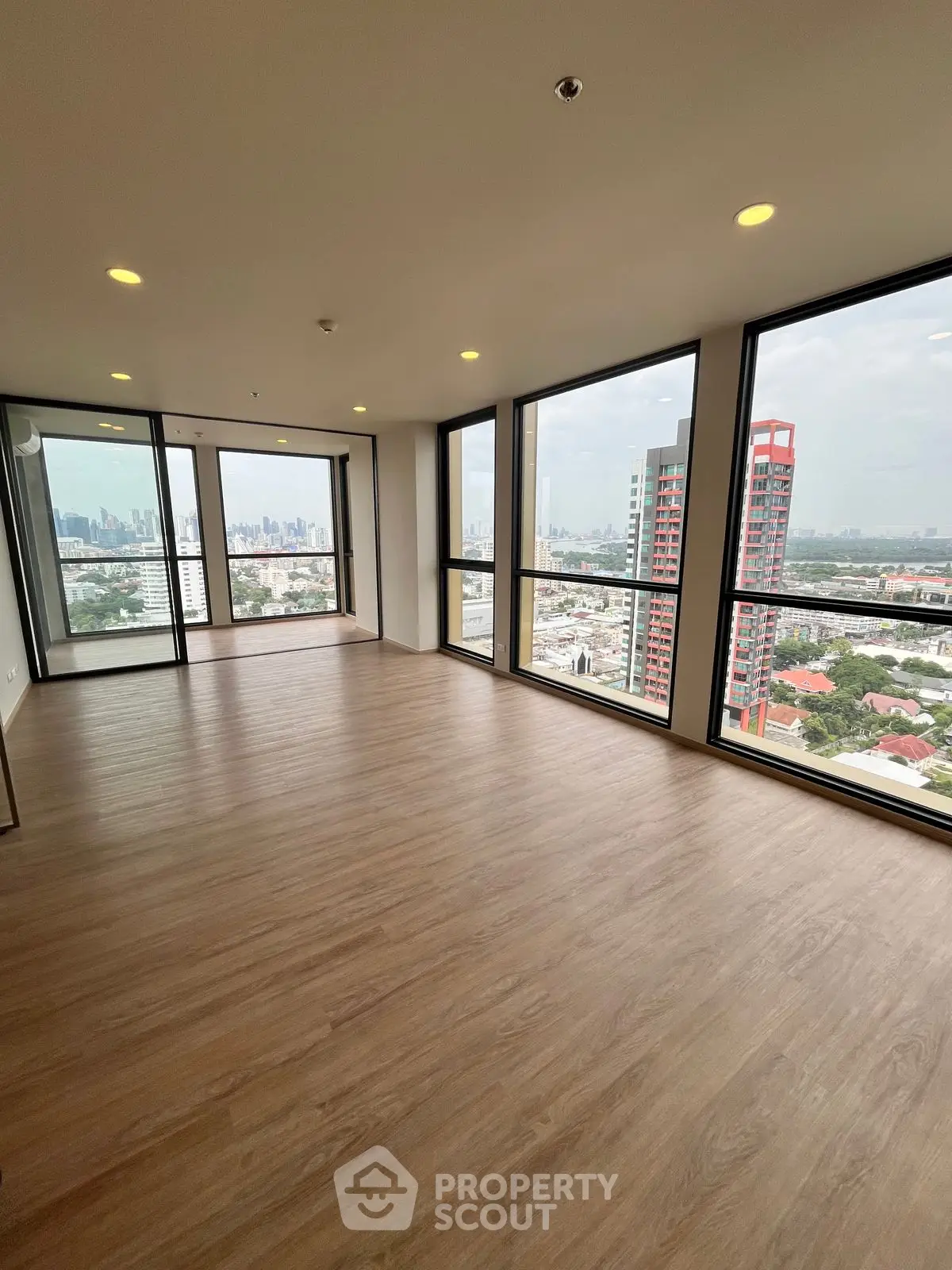 Spacious corner unit with panoramic city views and large windows in modern high-rise.