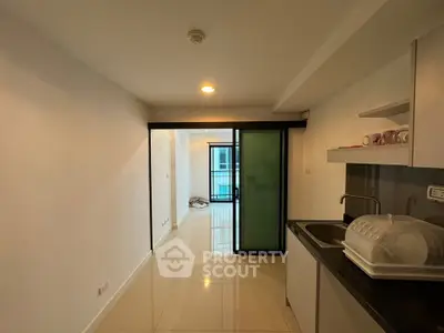 Modern apartment interior with sleek kitchen and sliding glass doors leading to balcony.