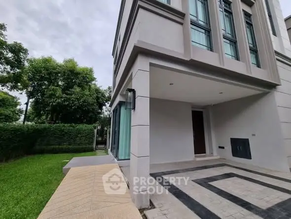 Modern residential building exterior with lush green garden and stylish entrance.