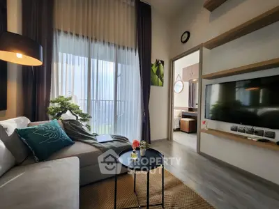 Modern living room with stylish decor and natural light, featuring a cozy sofa and wall-mounted TV.