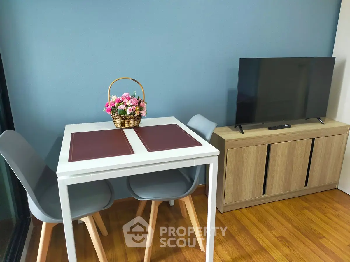Modern living room with sleek furniture and stylish decor, featuring a flat-screen TV and a cozy dining area.