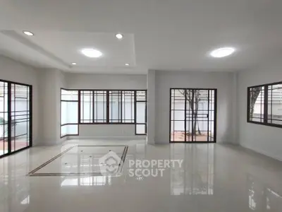 Spacious modern living room with large windows and elegant ceiling lights.
