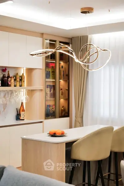 Modern kitchen with stylish lighting and breakfast bar, featuring elegant cabinetry and a cozy atmosphere.