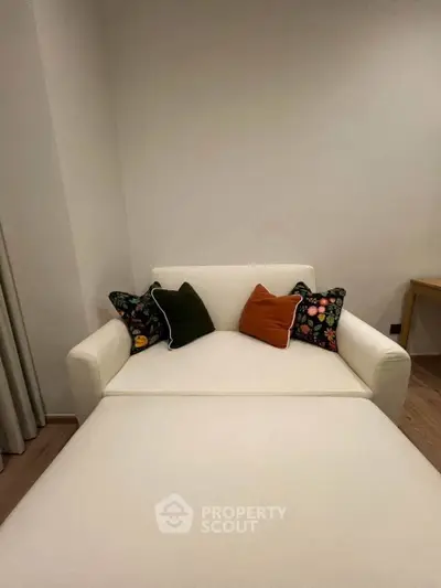 Cozy living room with a stylish white sofa and colorful cushions, perfect for relaxation.