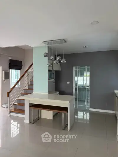 Modern open-plan living space with sleek staircase and stylish lighting fixtures.