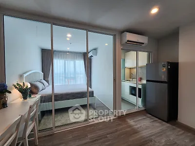 Modern apartment interior with bedroom and kitchen, featuring sleek design and natural light.