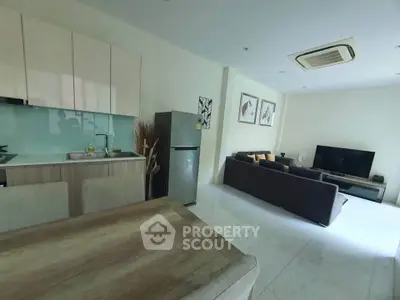 Modern open-plan living room and kitchen with sleek furniture and natural light.