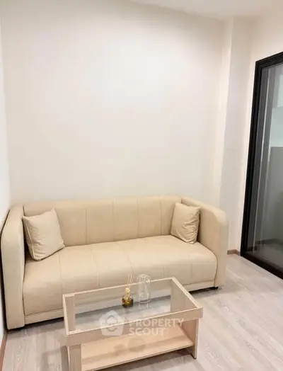 Cozy living room with beige sofa and glass coffee table in modern apartment.