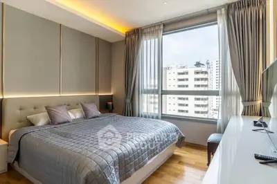 Luxurious bedroom with modern decor and large window offering city views.