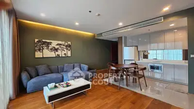 Spacious modern living room with open kitchen, featuring stylish furniture and elegant decor.