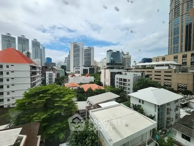 Stunning cityscape view from a high-rise building showcasing modern architecture and lush greenery.