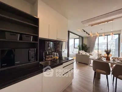 Modern open-layout kitchen and living room with elegant dining area and large windows.