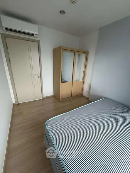 Cozy bedroom with striped bedding and wooden wardrobe, perfect for a minimalist lifestyle.