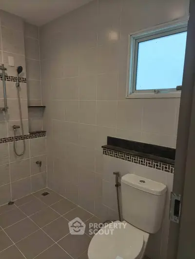 Modern bathroom with sleek tile design and shower area in a contemporary home.