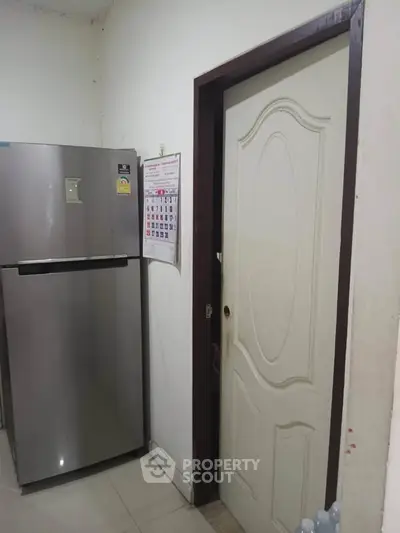 Compact kitchen space with modern fridge and calendar on wall.