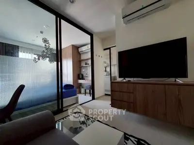 Modern living room with sleek furniture and large TV, adjacent to a cozy bedroom.