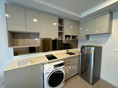 Modern kitchen with sleek cabinets, built-in appliances, and washing machine in stylish apartment.