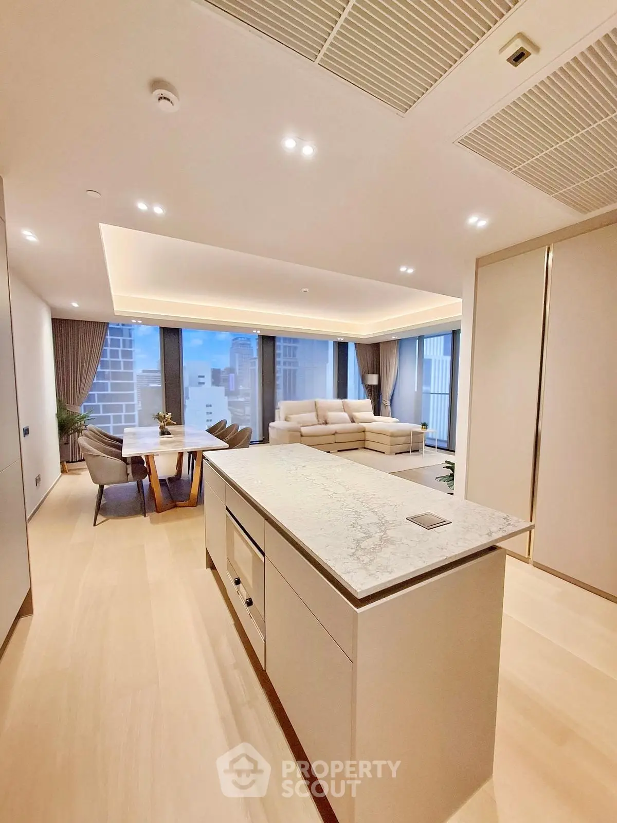 Luxurious open-plan living room with modern kitchen island and stunning city view.
