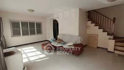 Spacious living room with cozy sofa and staircase, perfect for family gatherings.