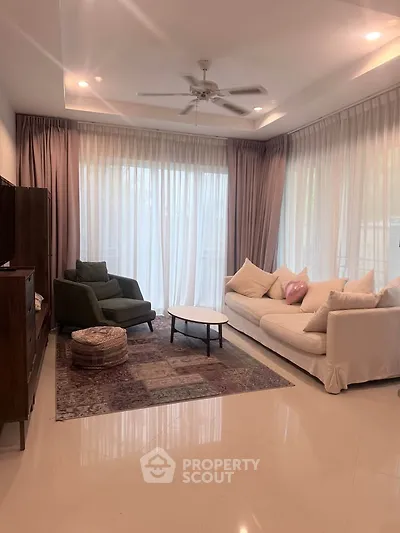 Elegant living room with plush sofas, large windows, and stylish decor in a modern home.