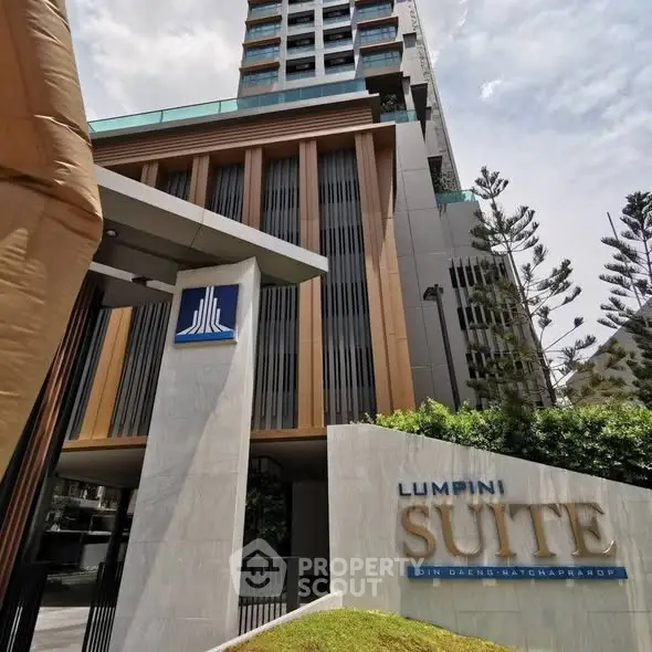 Modern high-rise building with lush greenery and elegant entrance signage.