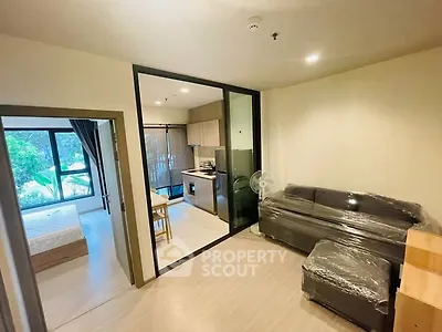 Modern apartment interior with open layout, featuring a cozy living room and adjacent kitchen area.
