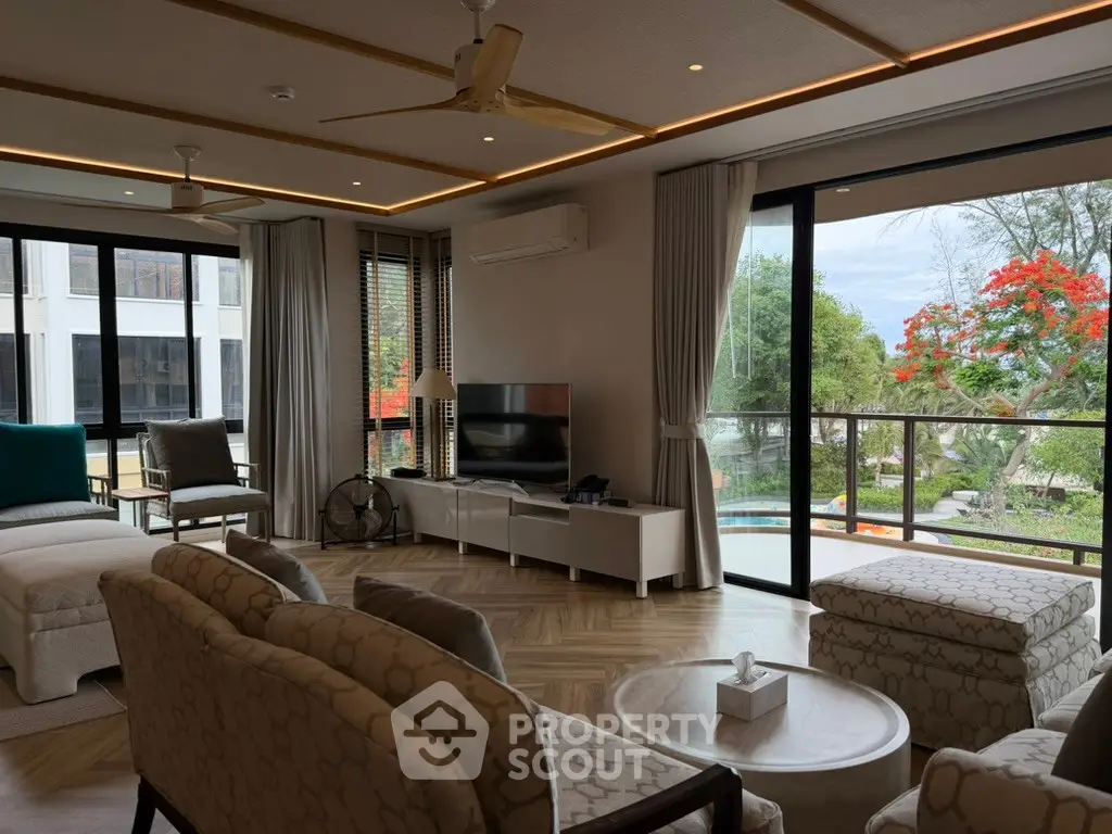 Spacious living room with modern decor and large windows overlooking a lush garden view.