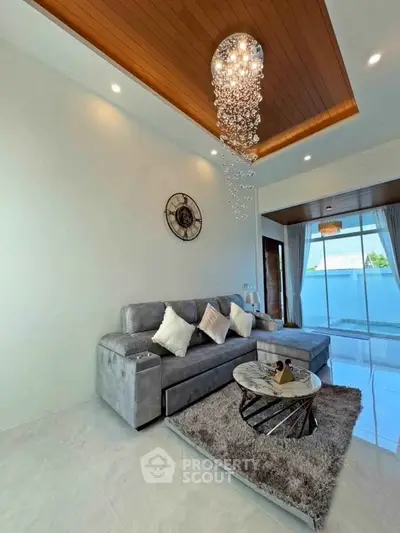 Luxurious living room with elegant chandelier and plush gray sofa in modern home.