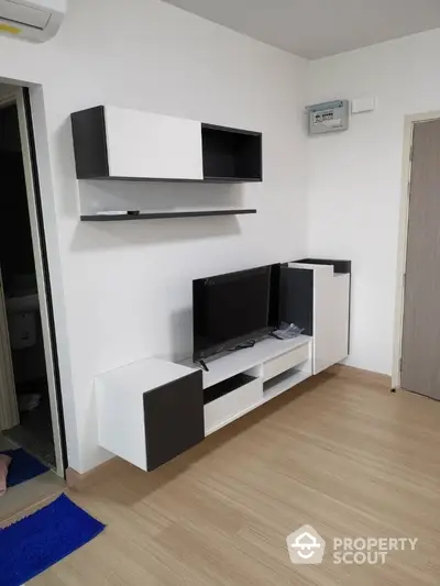 Modern living room with sleek black and white wall-mounted TV unit and wooden flooring.