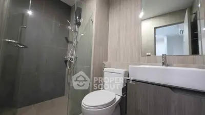 Modern bathroom with glass shower and sleek fixtures in contemporary apartment.