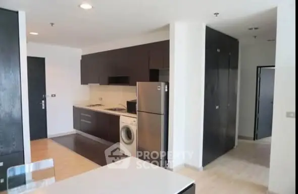Modern kitchen with sleek cabinets, stainless steel fridge, and washing machine in open layout.