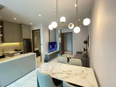Modern open-plan living room and kitchen with elegant lighting and marble dining table.