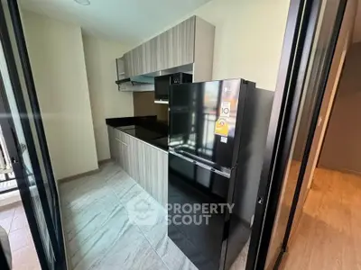 Modern kitchen with sleek cabinetry and black refrigerator in a stylish apartment.