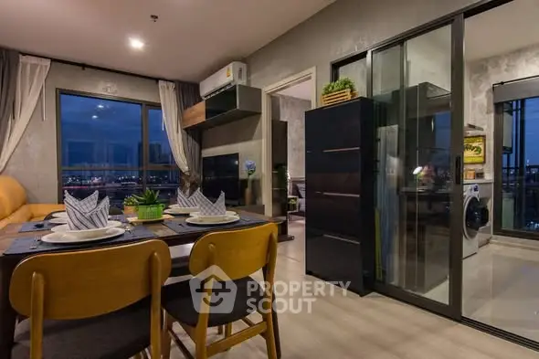 Modern open-plan living and dining area with city view and sleek kitchen appliances.