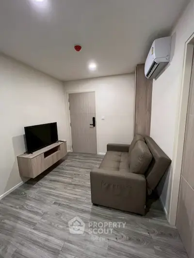 Modern living room with sleek design, featuring a comfortable sofa and wall-mounted TV, perfect for relaxation.