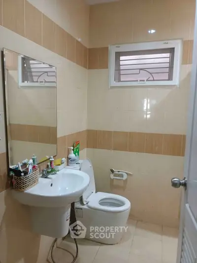 Modern bathroom with sleek fixtures and neutral tile design, featuring a large mirror and compact sink.