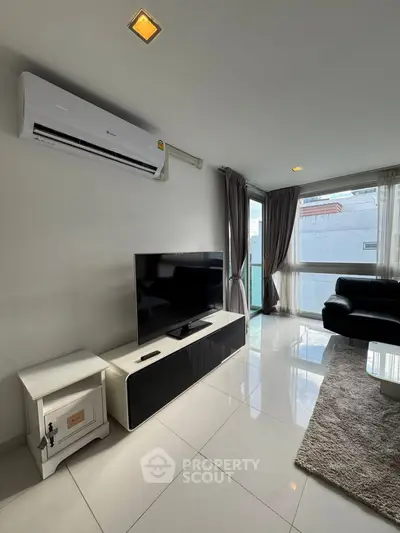 Modern living room with sleek furniture and large TV, featuring a bright and airy atmosphere.