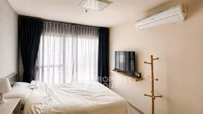 Modern bedroom with air conditioning and wall-mounted TV, featuring a cozy bed and elegant curtains.