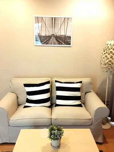 Cozy living room with stylish sofa, striped cushions, modern lamp, and framed artwork on wall.