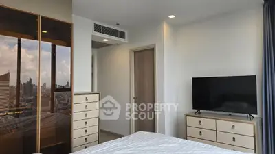 Modern bedroom with city view, featuring sleek furniture and a large window for natural light.
