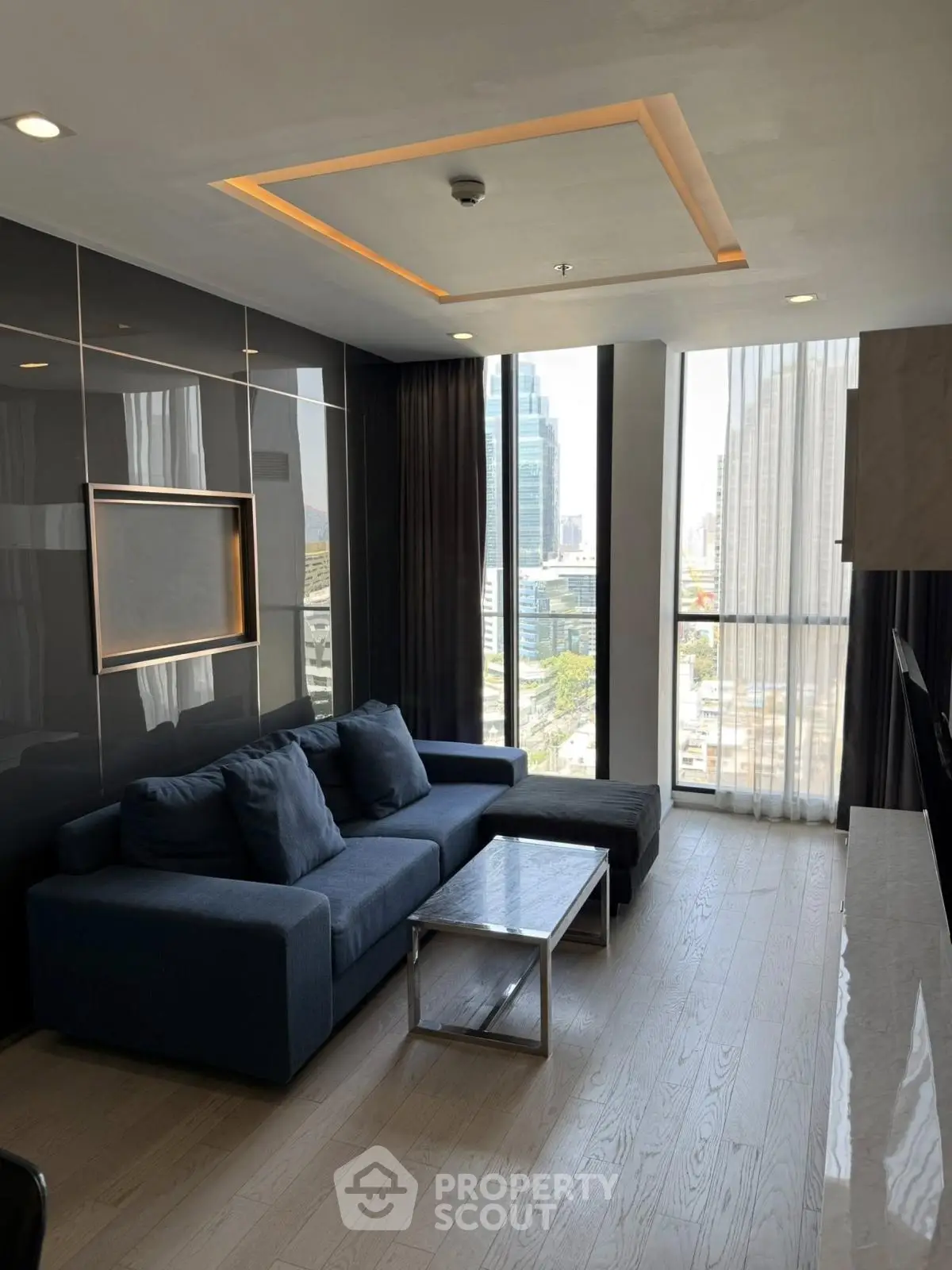 Modern living room with sleek design, large windows, and city view, featuring a stylish sofa and elegant decor.