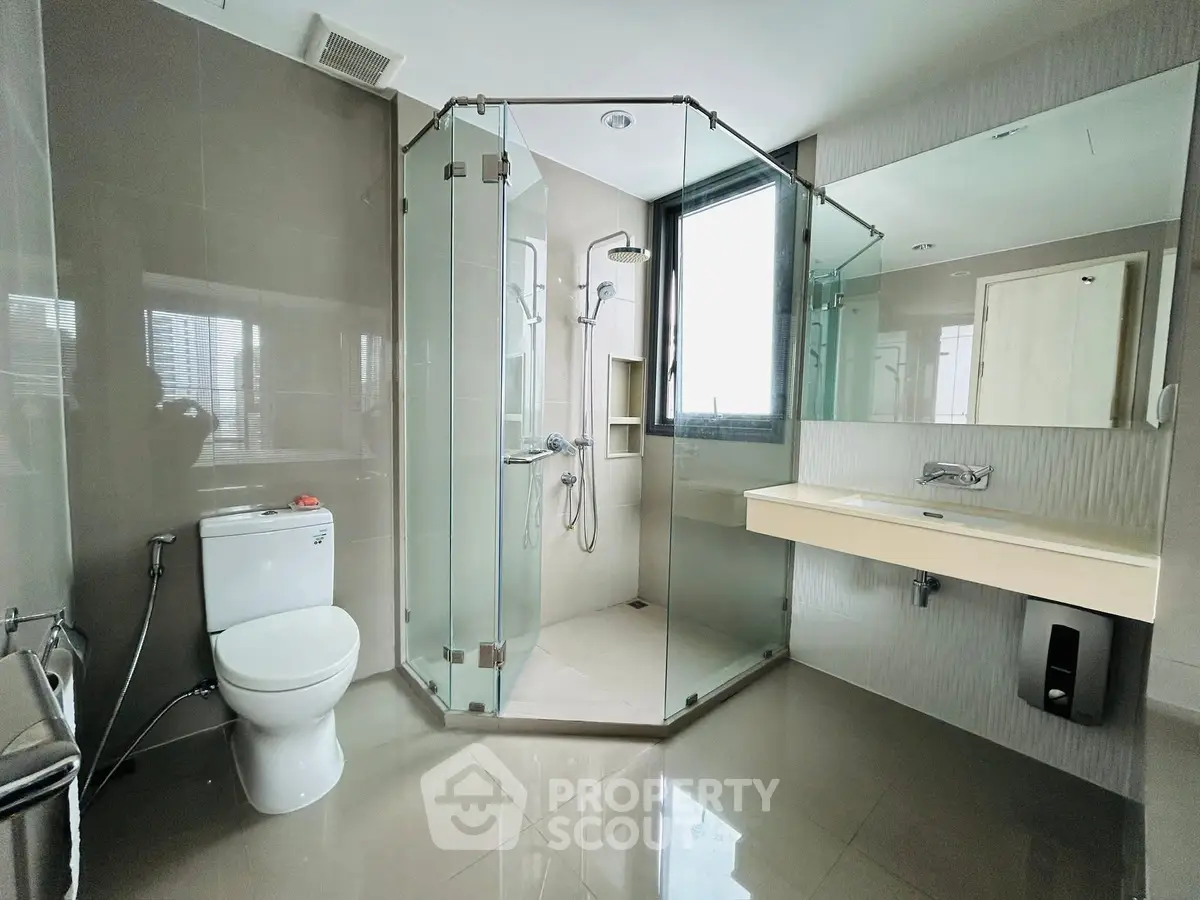 Modern bathroom with glass shower and sleek fixtures in luxury apartment.