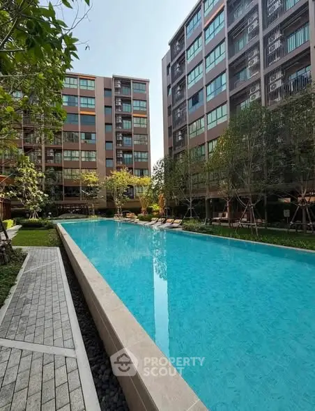 Luxurious apartment complex with a stunning outdoor pool and lush greenery.